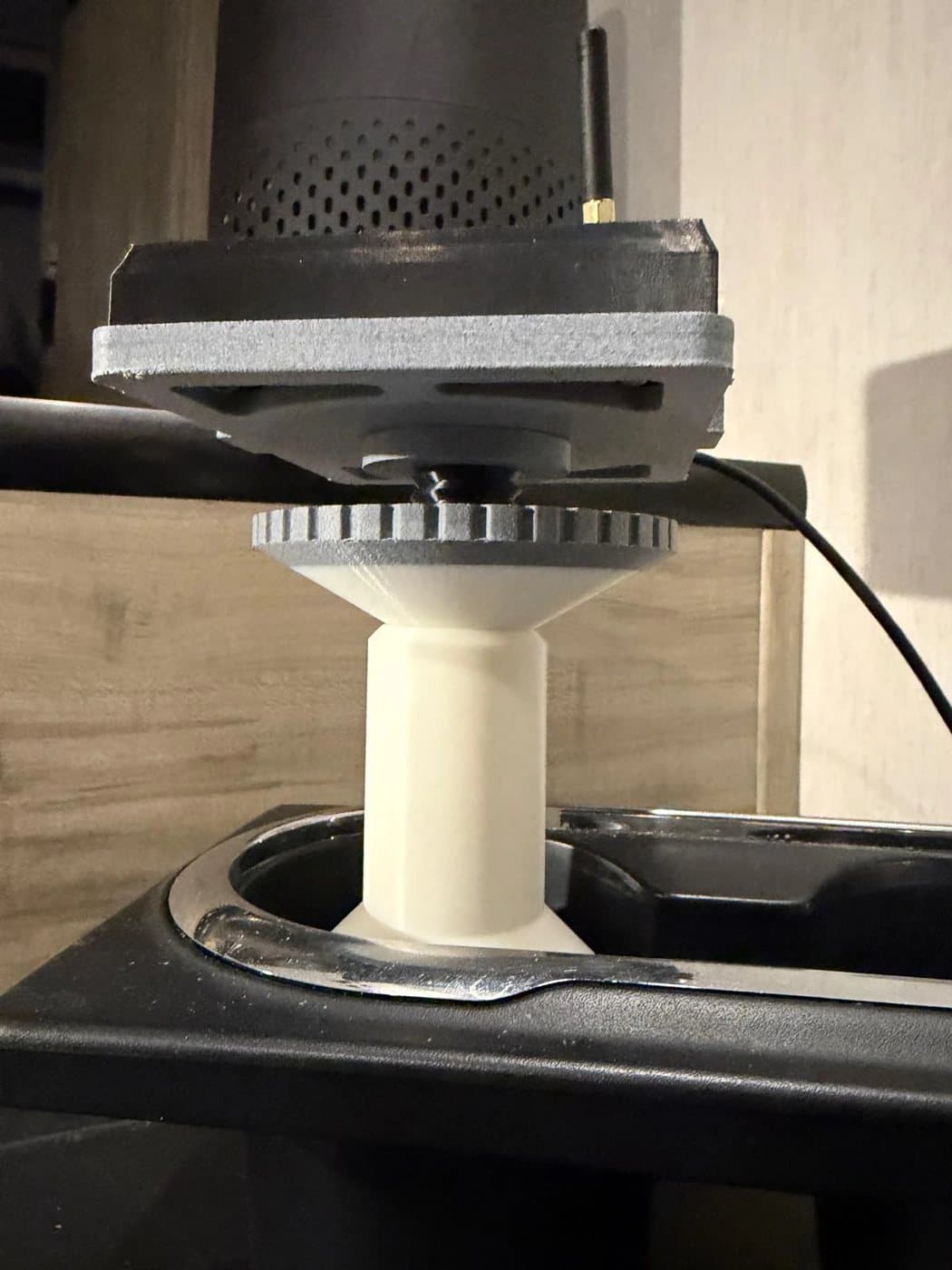 A Console clipped into its car mount, standing in a cup holder: the thumb wheel under the tray